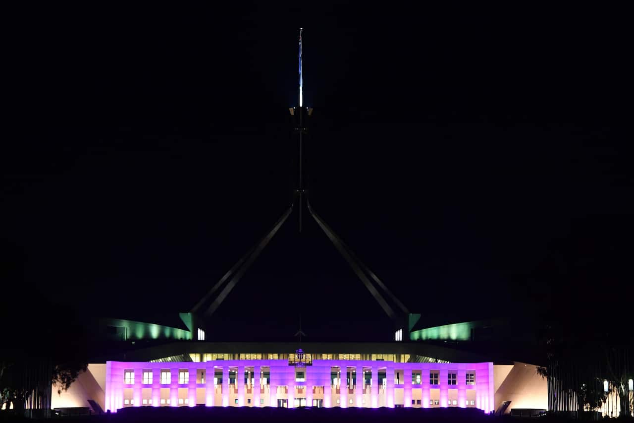 Federal Parliament House is lit up in the colour purple.