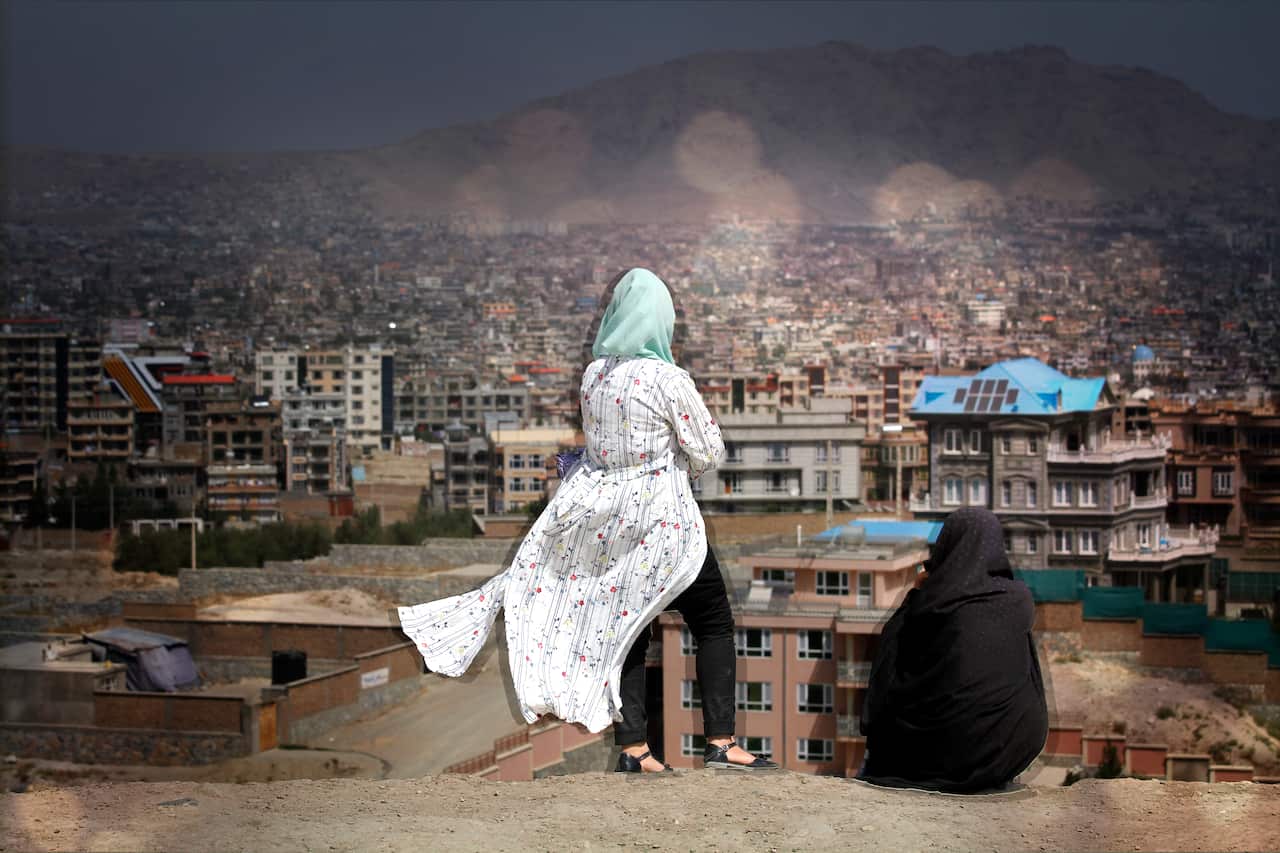 Two women look out at the Kabul skyline.