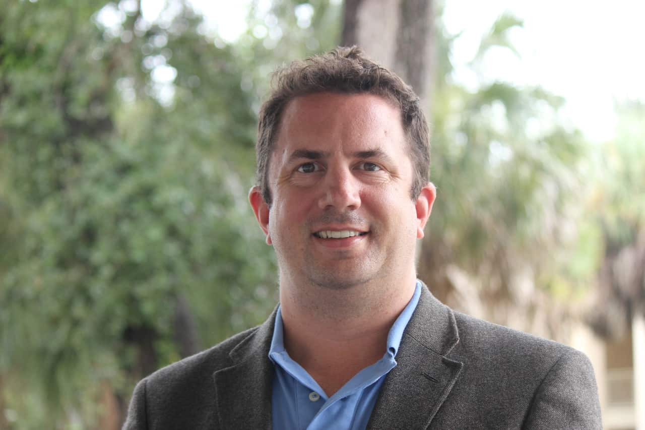 A middle-aged white man wearing a blazer jacket and blue shirt 