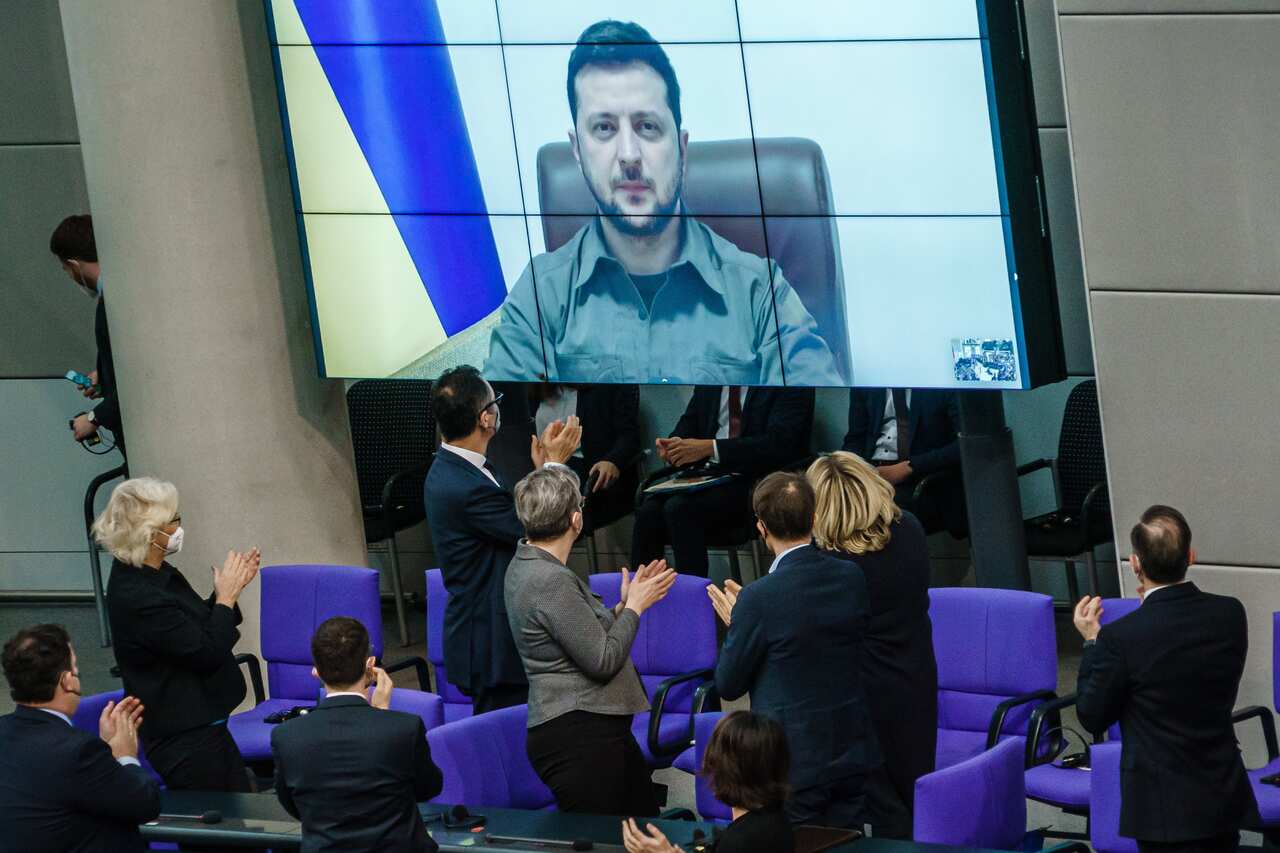 Ukrainian President Volodymyr Zelenskyy is seen on a screen as members of Germany's parliament applaud him.