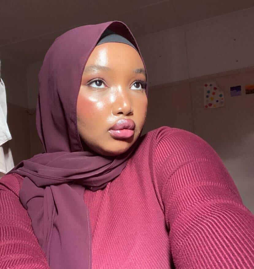 A woman wearing a maroon hijab and matching sweater