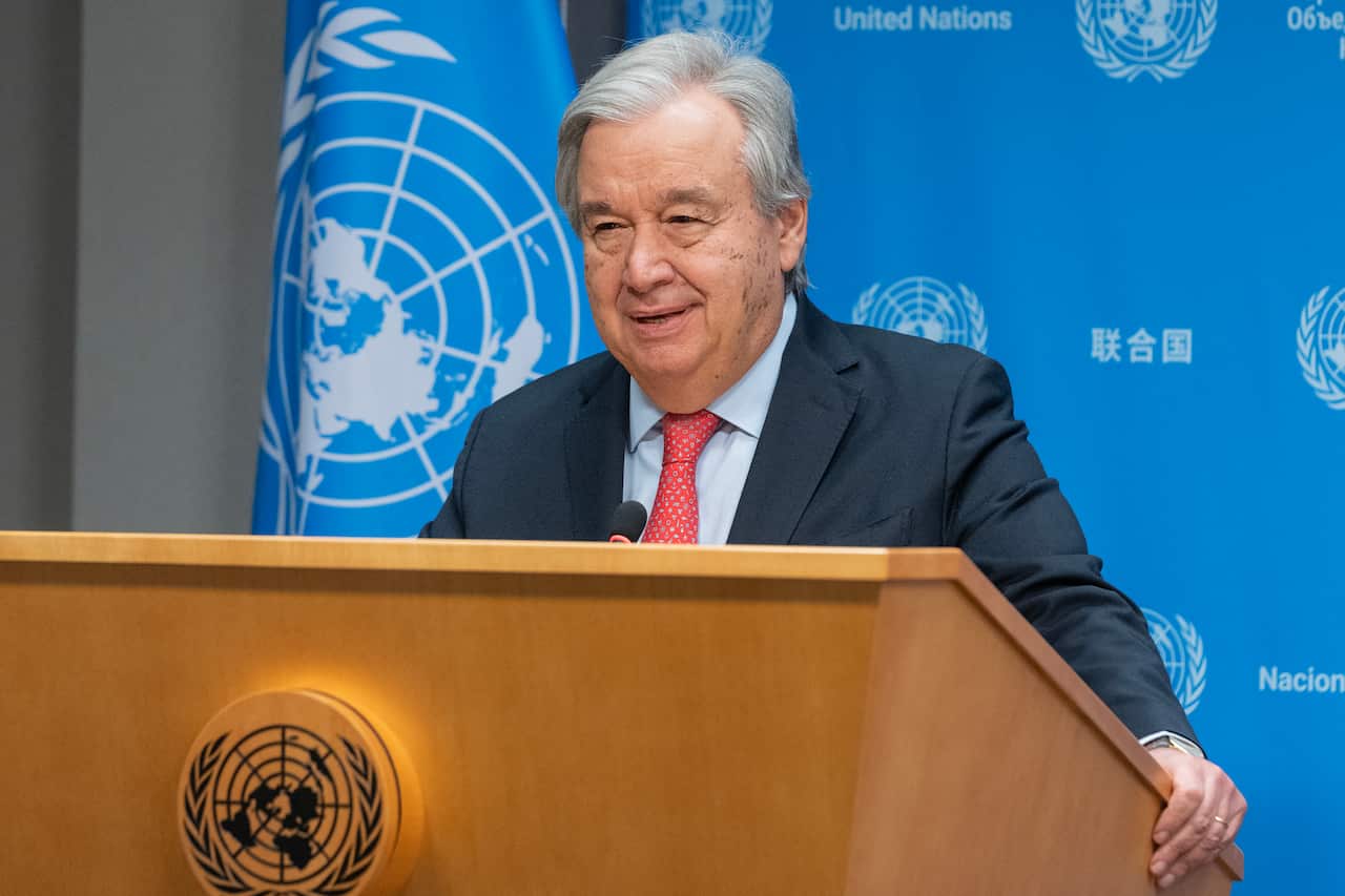 A man standing behind a podium. The United Nations logo is behind him.