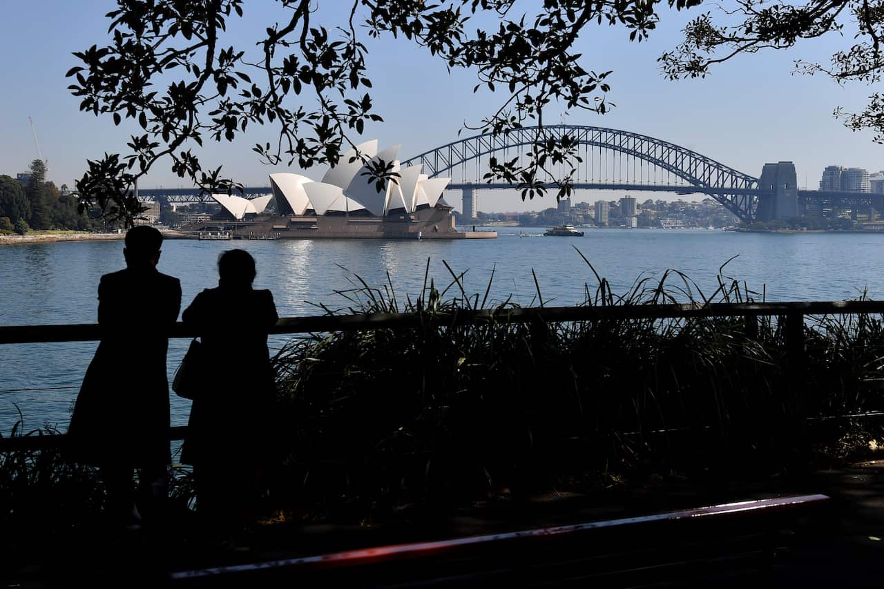 People standing and looking out at the Sydney Opera House and Sydney Habour Bridge.