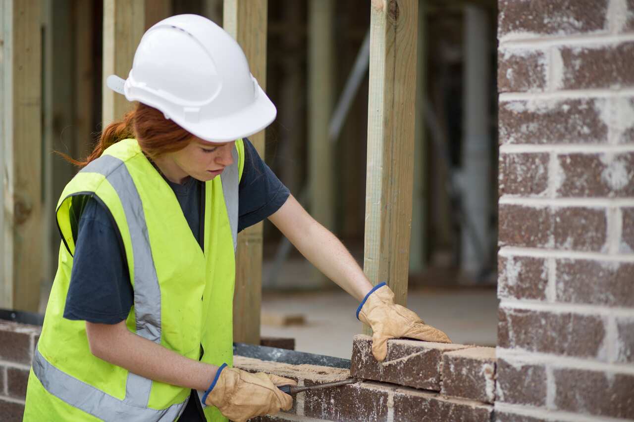 Woman bricklayer preparing laying bricks on wall