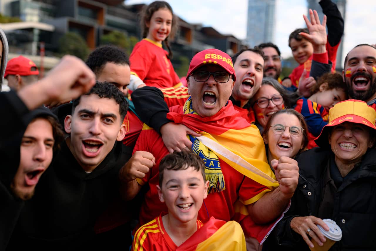 A group of people cheering excitedly, many wearing red and yellow.