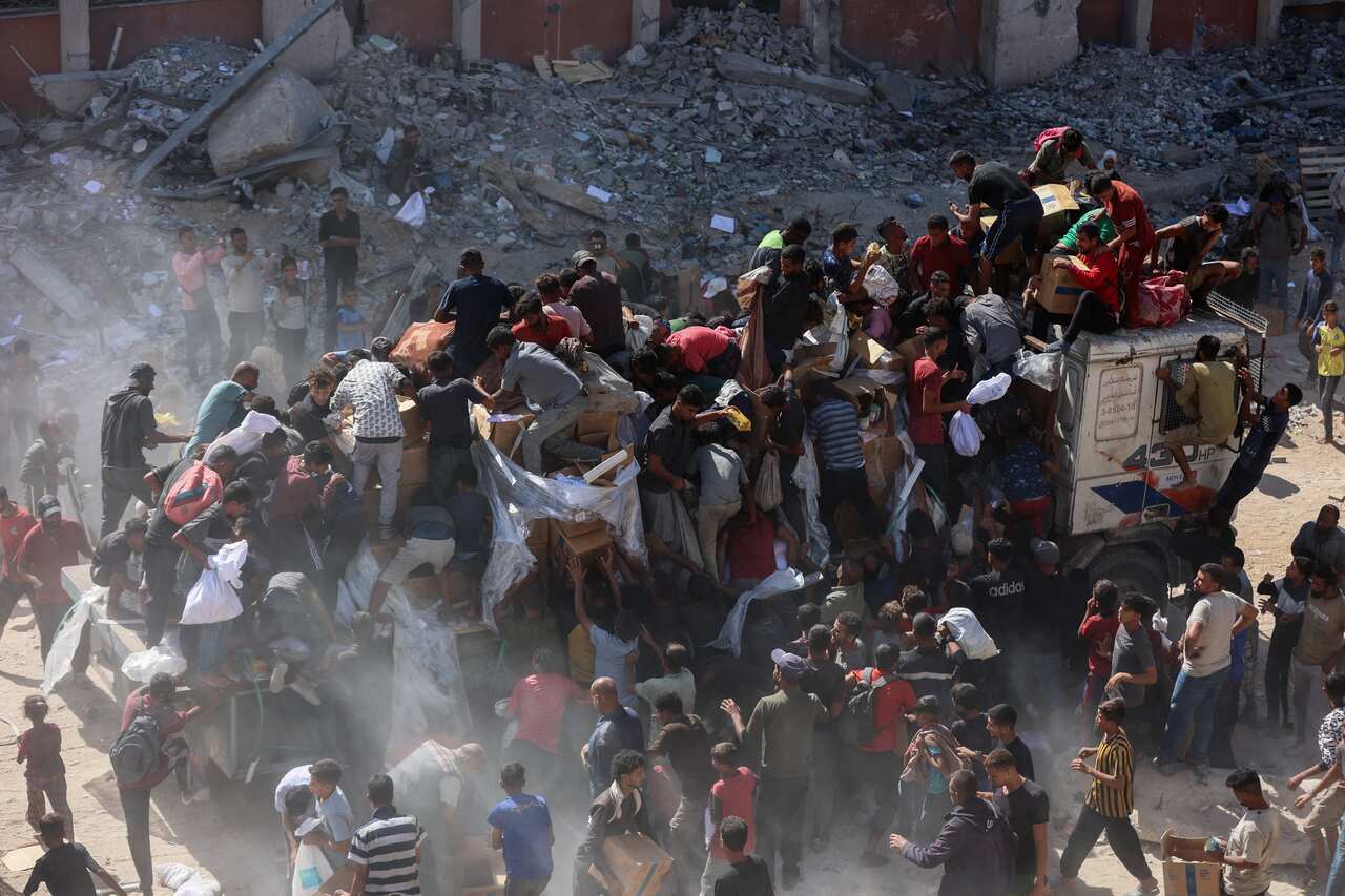 People rush to receive food parcels from aid trucks