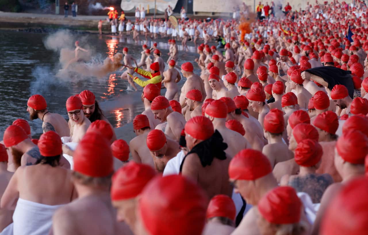 Swimmers enter the water during the annual nude winter solstice swim during Hobart's Dark Mofo festival at Long Beach in Sandy Bay, Tasmania, Wednesday, 22 June 2022.