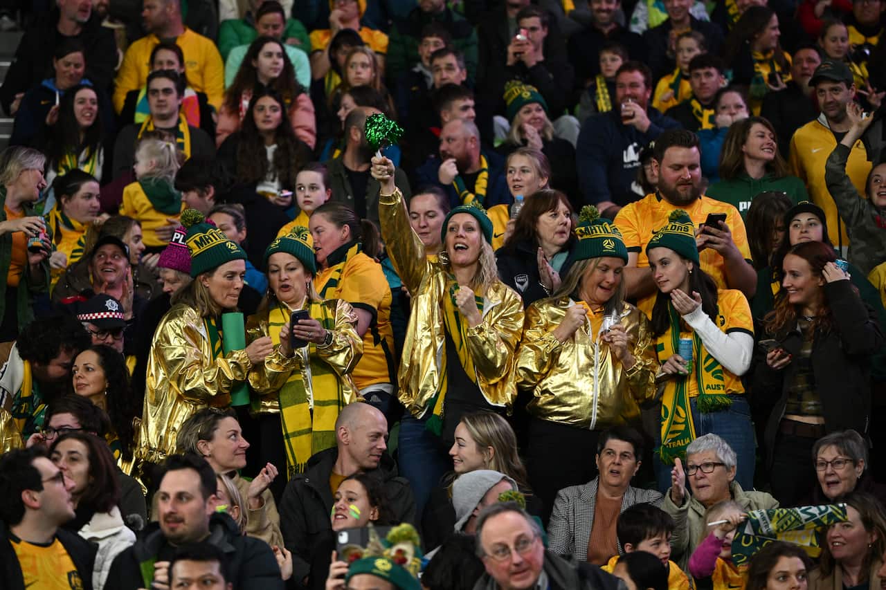A crowd of people in green and gold celebrating.