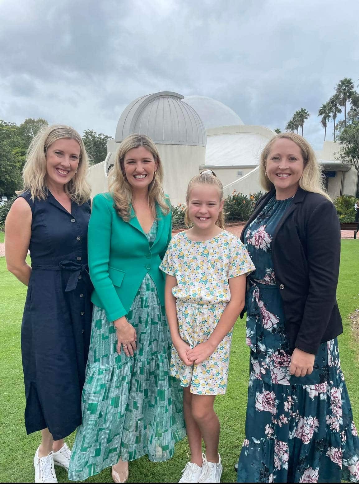 A group of three women and a girl stand outside a building with a domed roof