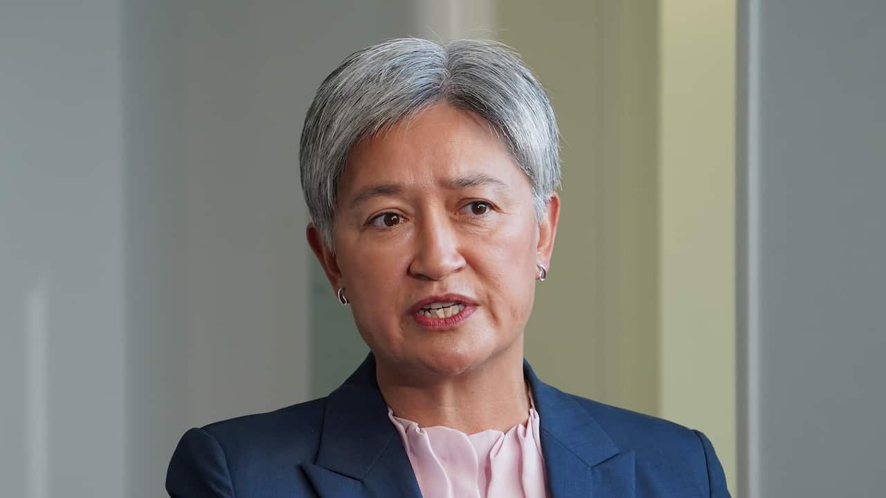 Penny Wong speaking in front of yellow and white walls.