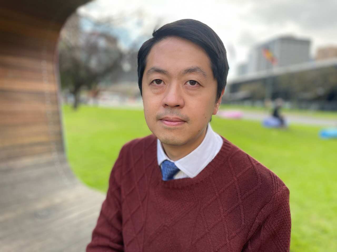 Ted Hui wearing a maroon jumper standing outside 