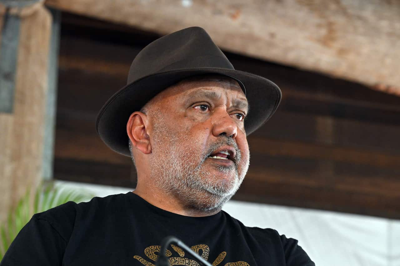 A man standing at a lectern while speaking in front of microphones.