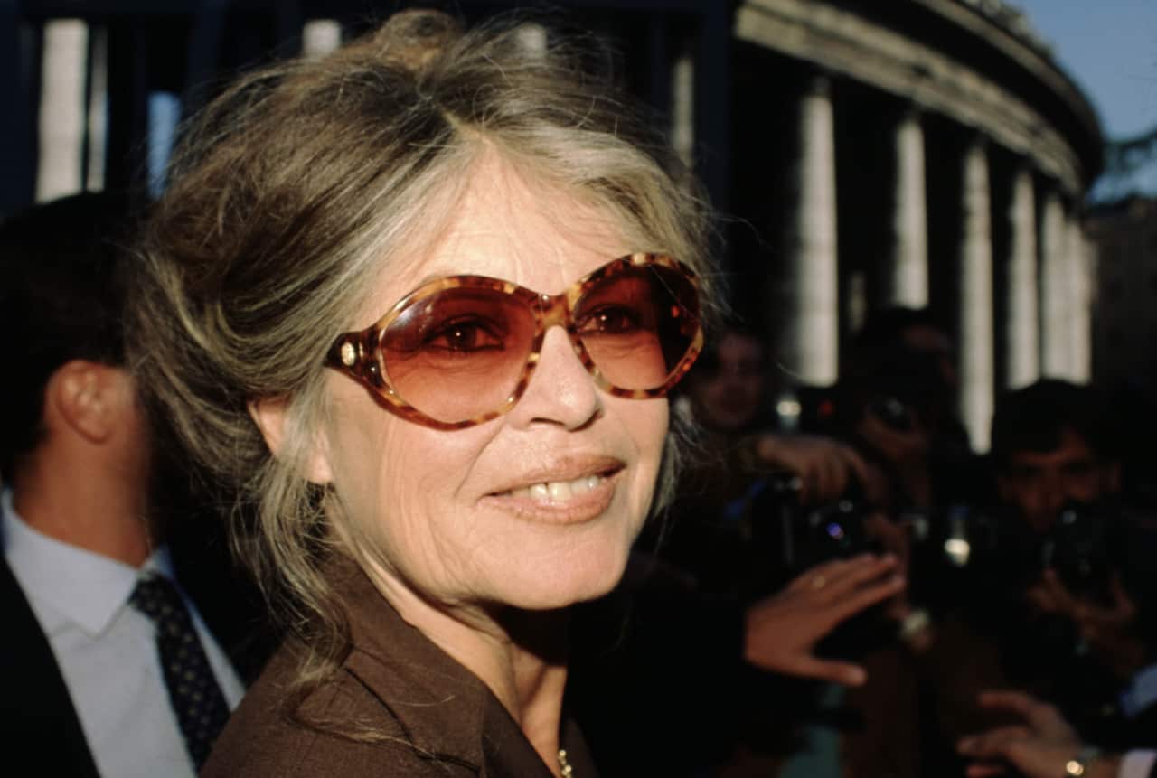 An older white woman with light brown and blonde hair and wearing sunglasses.