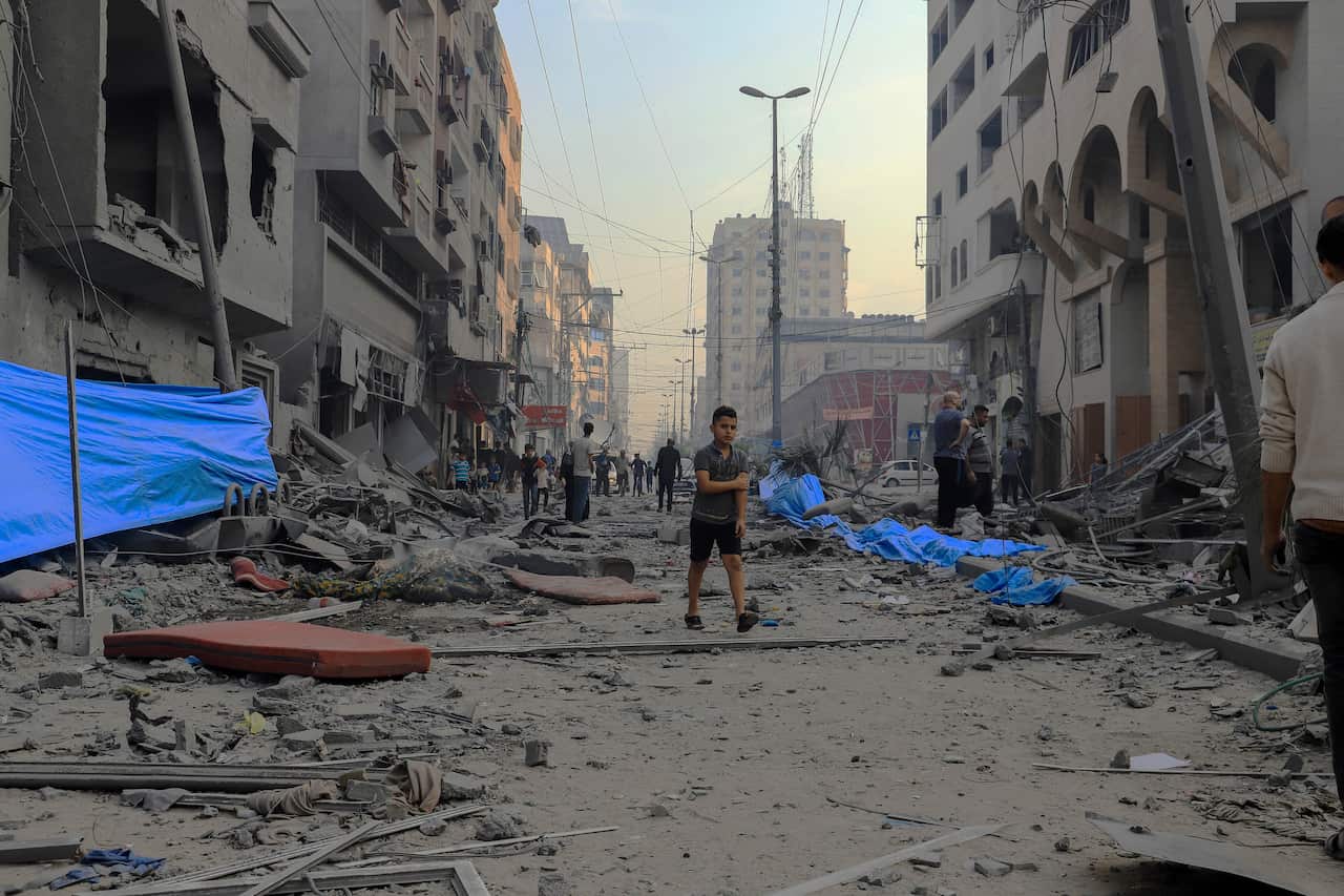 People walking along a street covered in debris and ash.