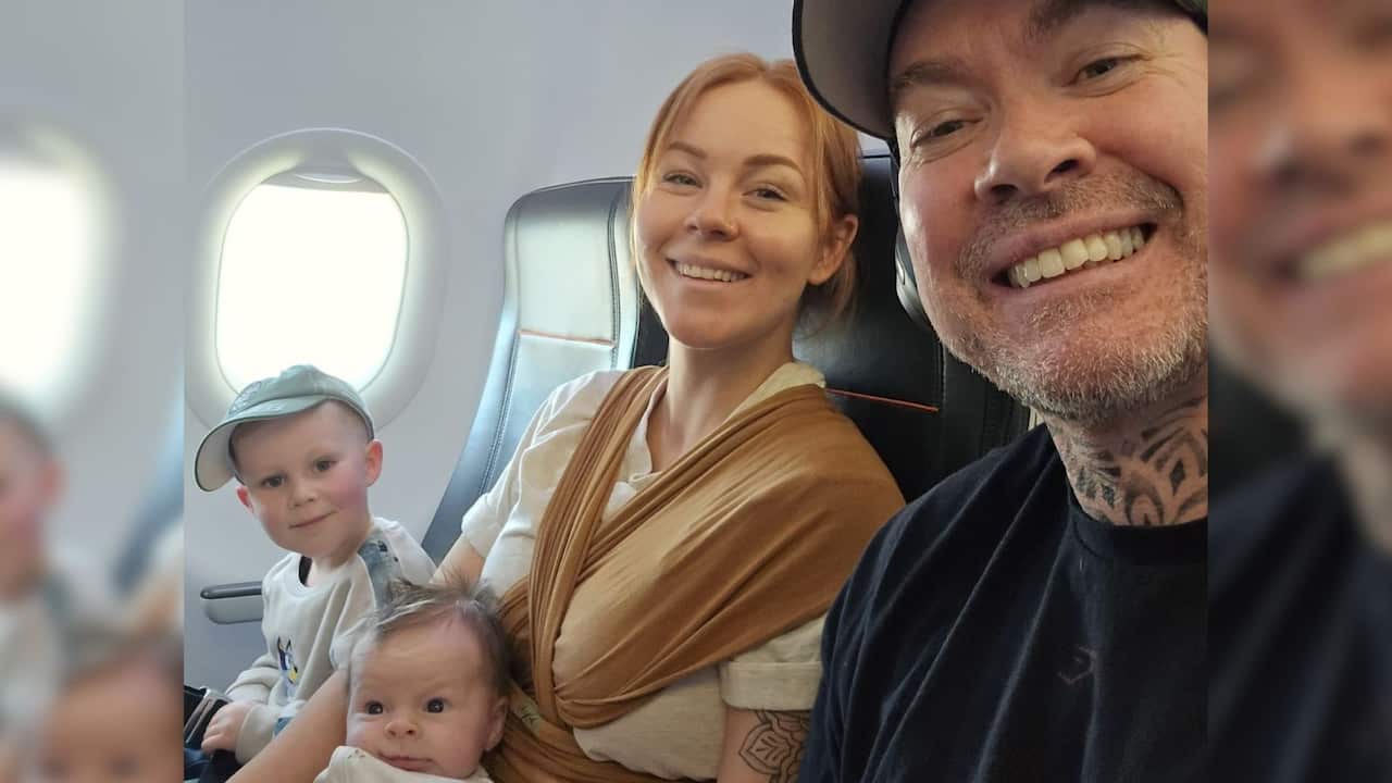 young parents (a woman and a man) sit on a plane with their toddler and baby