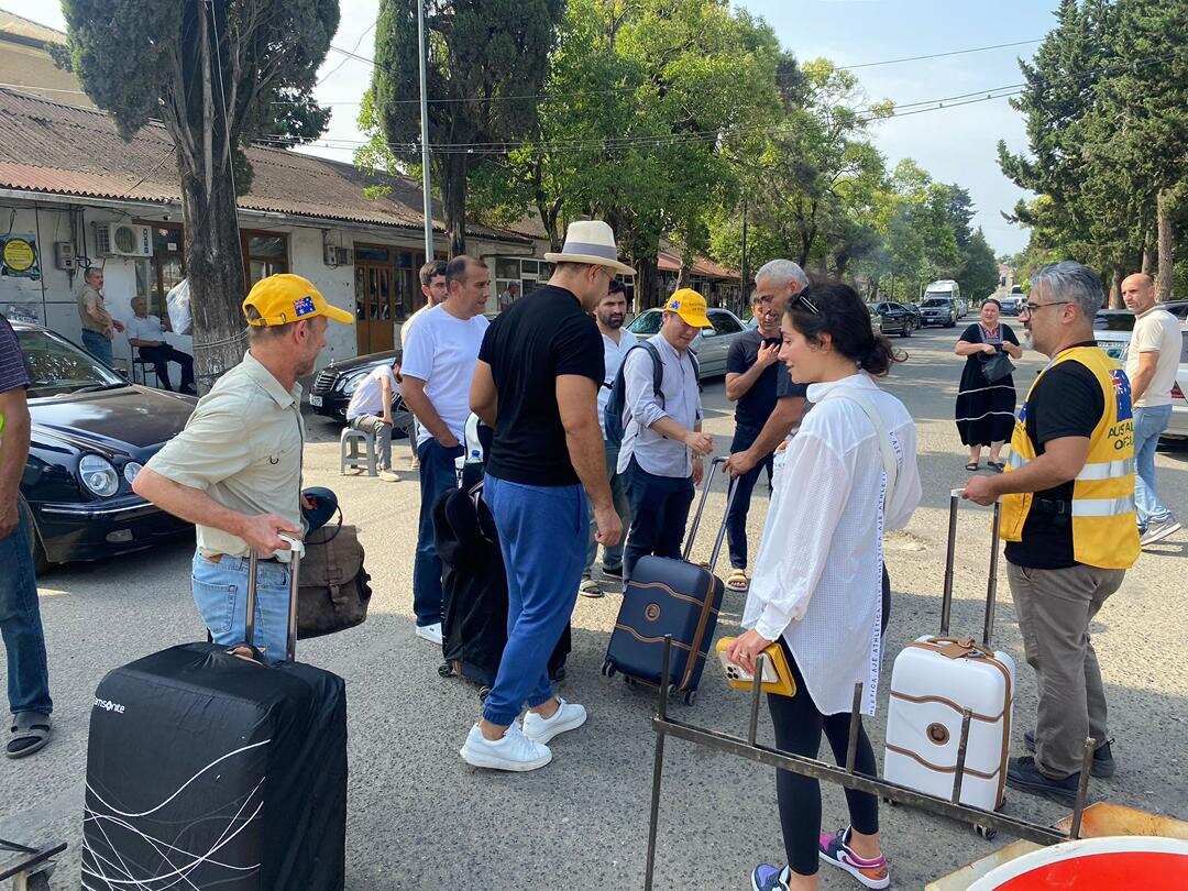 People are standing outside with suitcases.