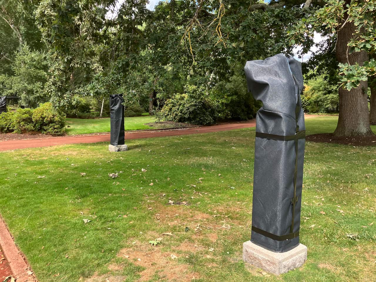 Two statues in a garden that have been covered.