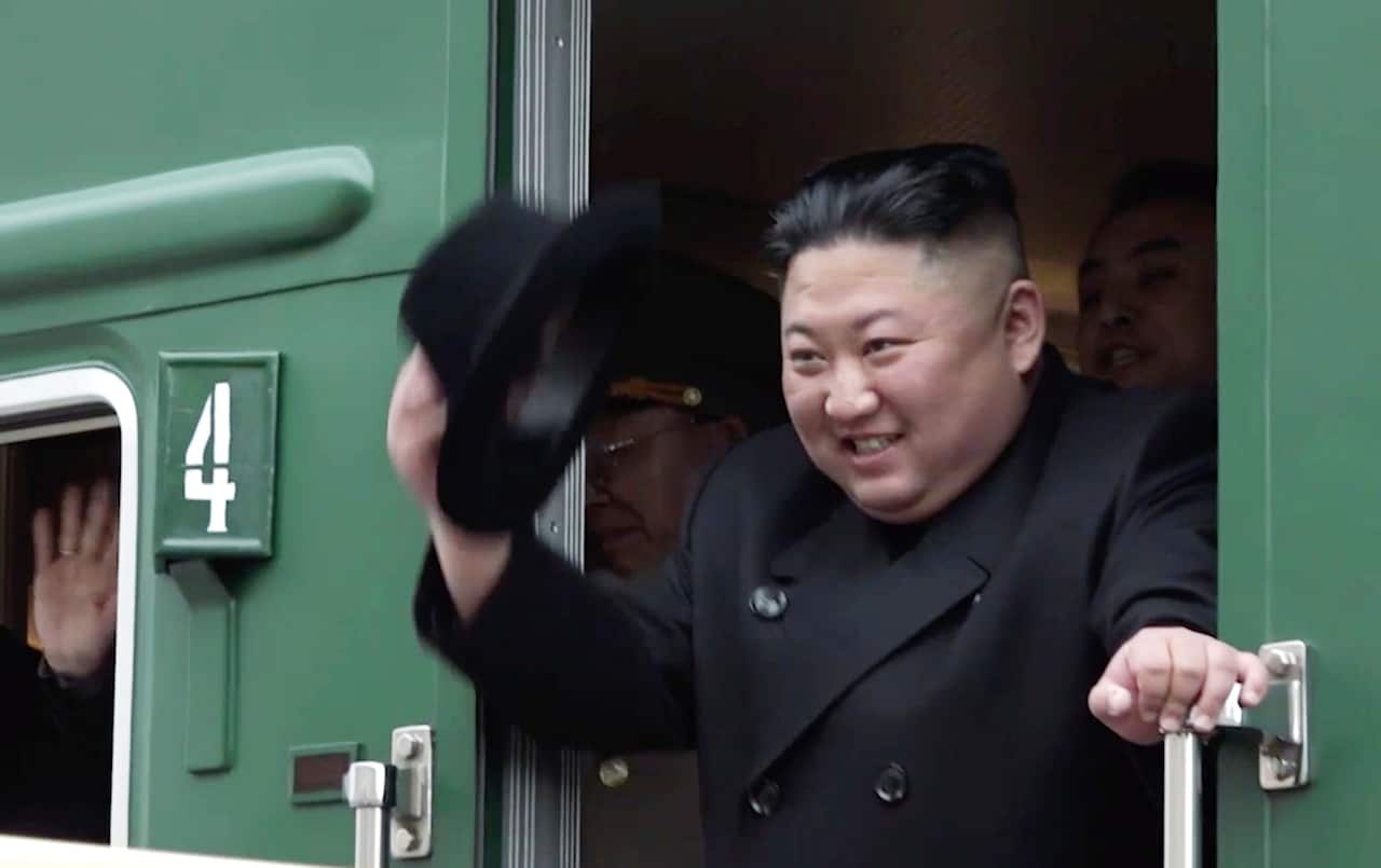 Kim Jong-un waves from a green train.