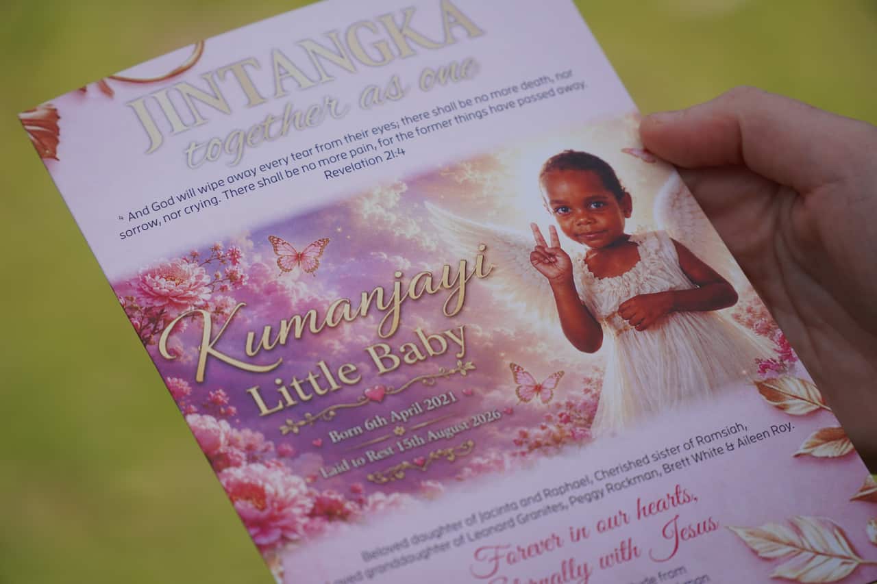 A pink funeral pamphlet with a picture of a young girl with her hand raised in a peace sign and the text 'Kumanjayi Little Baby'.