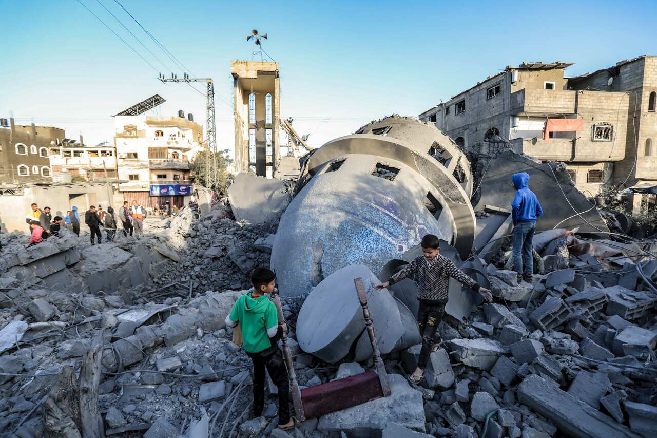 Children looking through the rubble of a destroyed building.