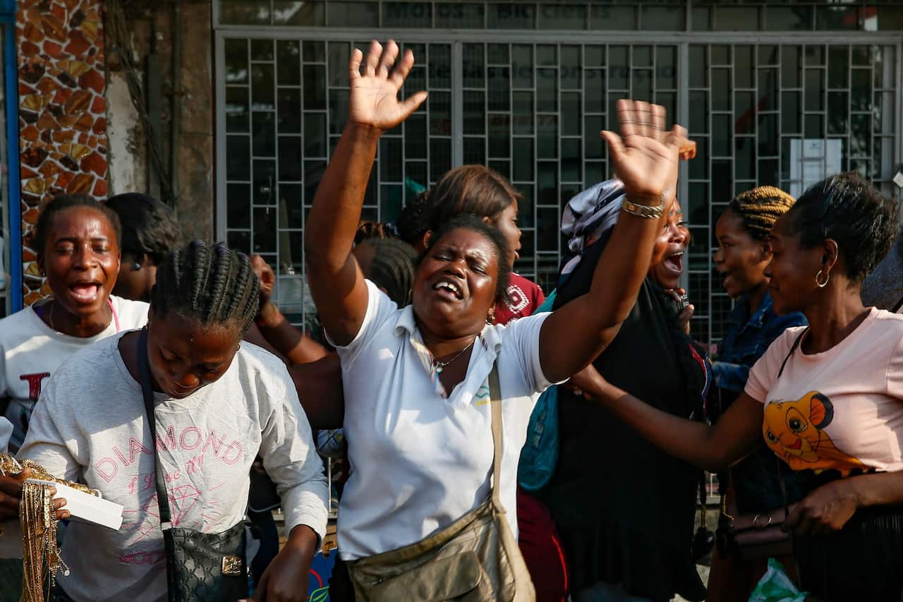 A woman raises her arms as she sings her grief over the death of José Eduardo Dos Santos.