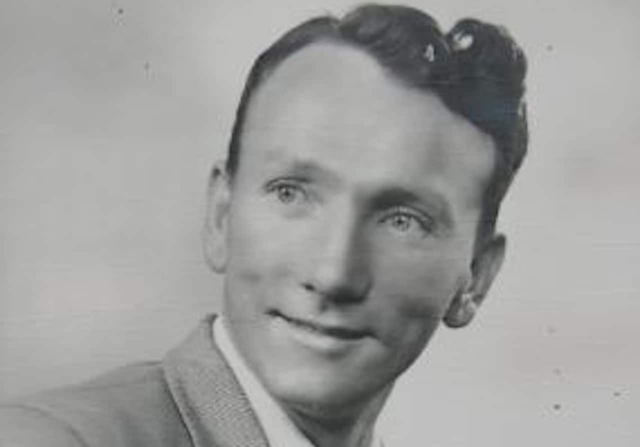 A young man is smiling in a black and white photo.