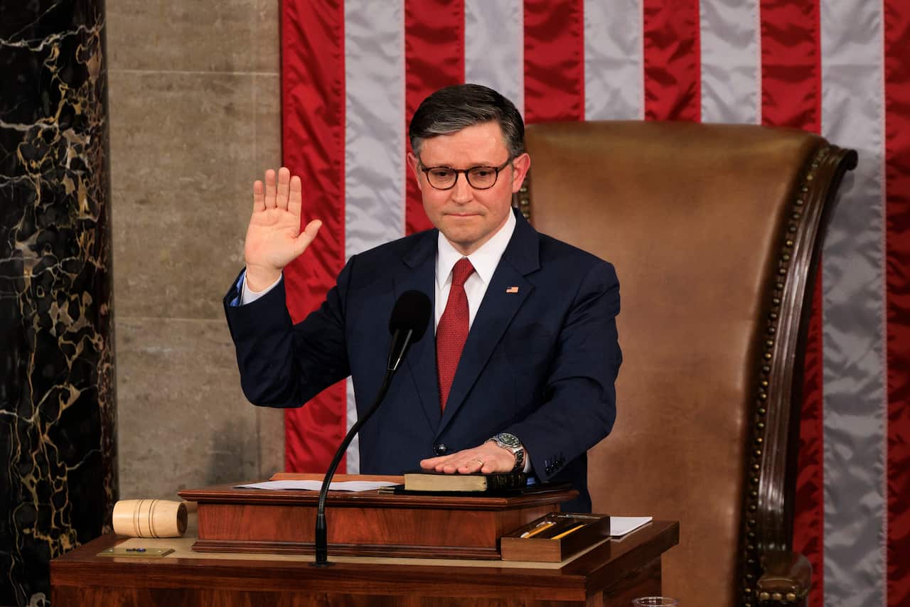 Mike Johnson holding his hand on a bible and swearing with his hand raised.