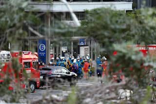 A group of people in high-vis clothes and hard hats gather outside a building.