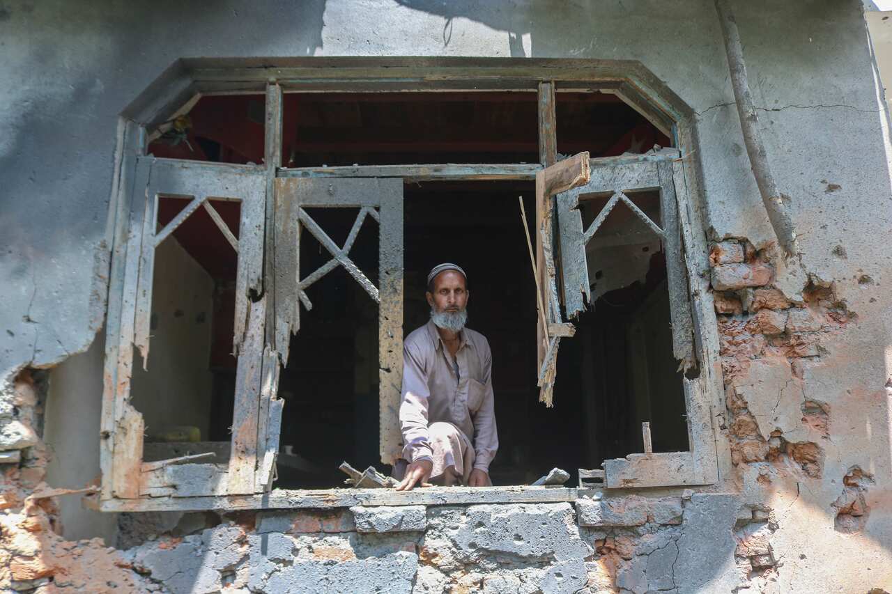A man peering through the rubble of a building.