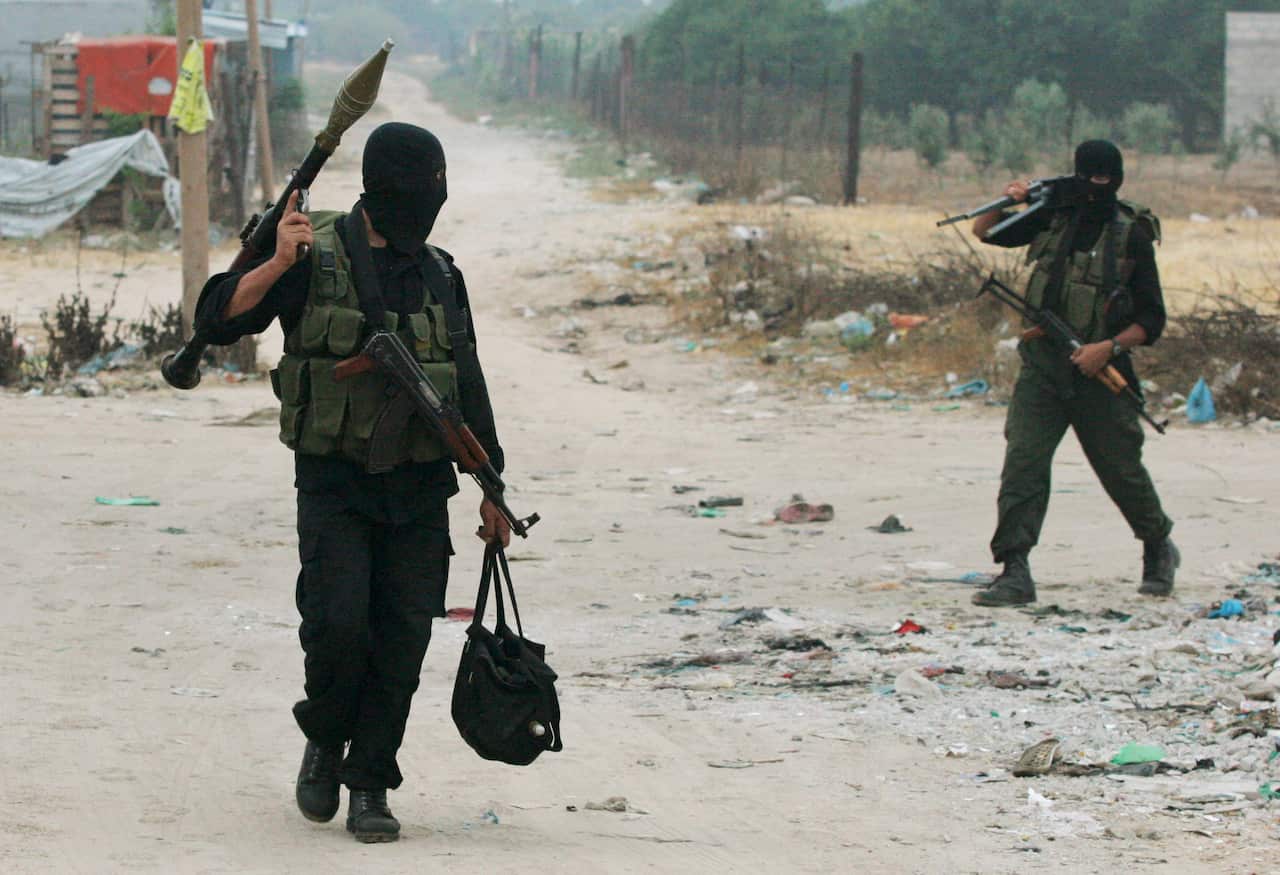 Two gunman carry equipment.