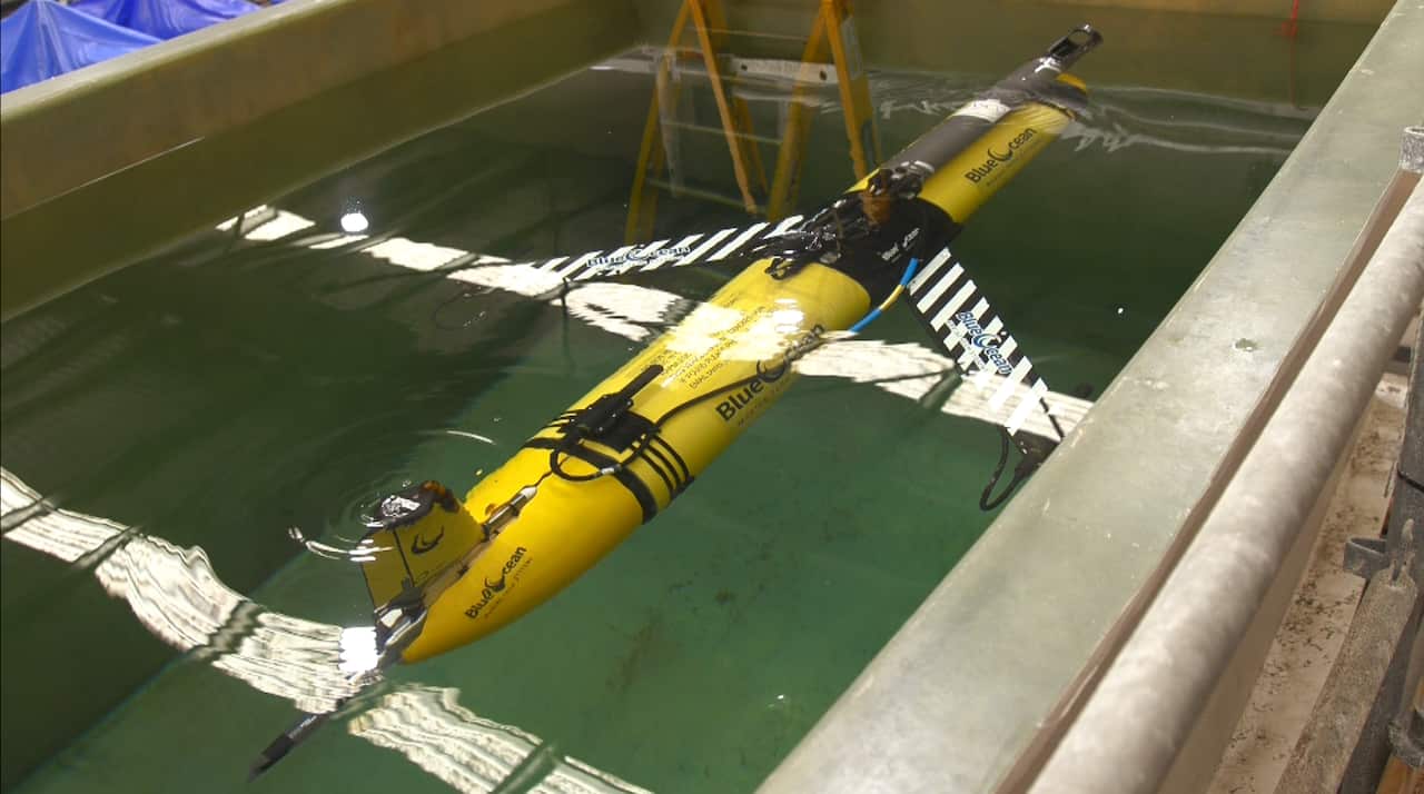 Yellow underwater drone in the water, undergoing testing. 