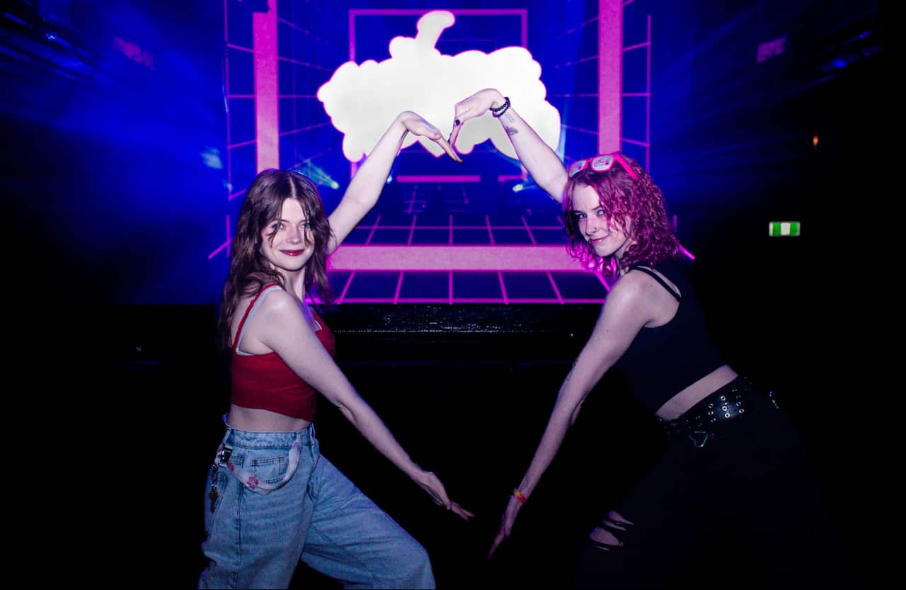 Two young women hold up their arms in the shape of a heart 