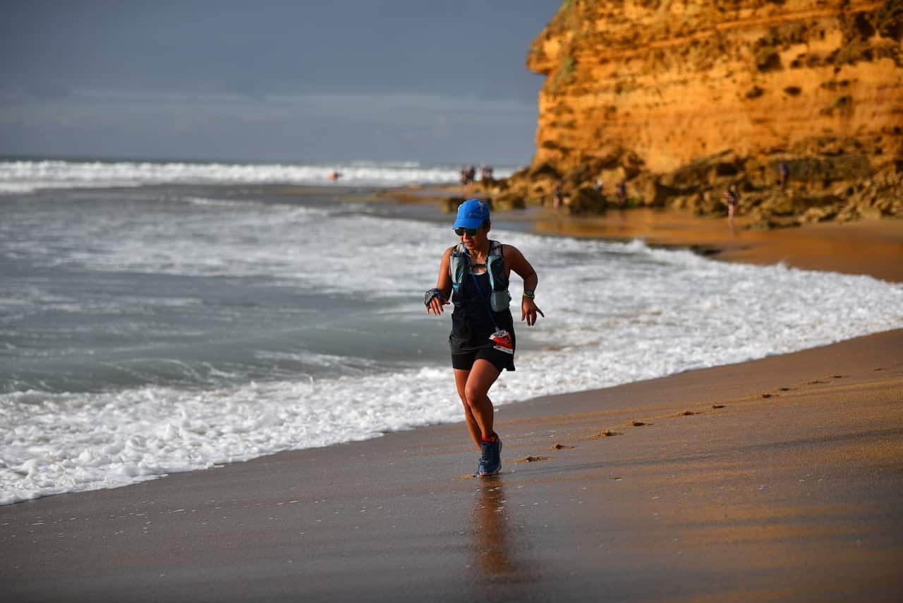 A woman runs on the beach in active wear.