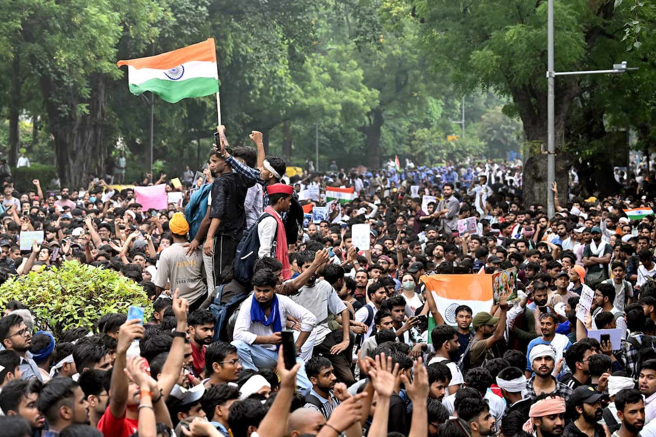 People gather at a square to protest with some protesters holding up the Indian flag