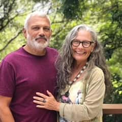 A middle-aged couple embrace as they smile at the camera.