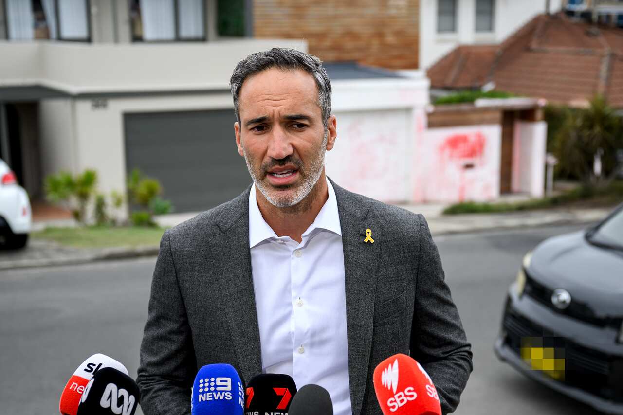 A man in a grey suit speaks to the media. 