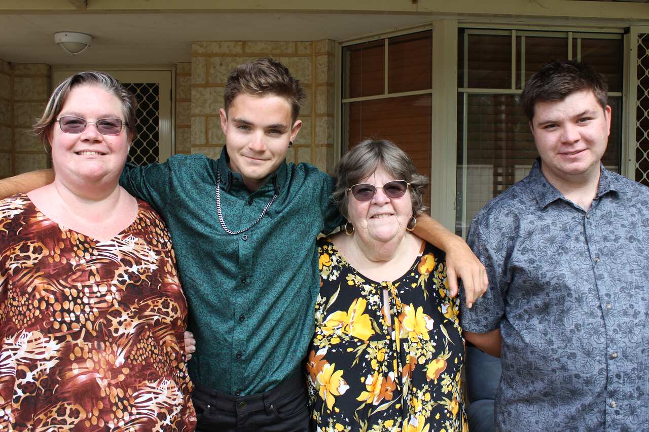 Two women and two men standing in a row outside a house. 
