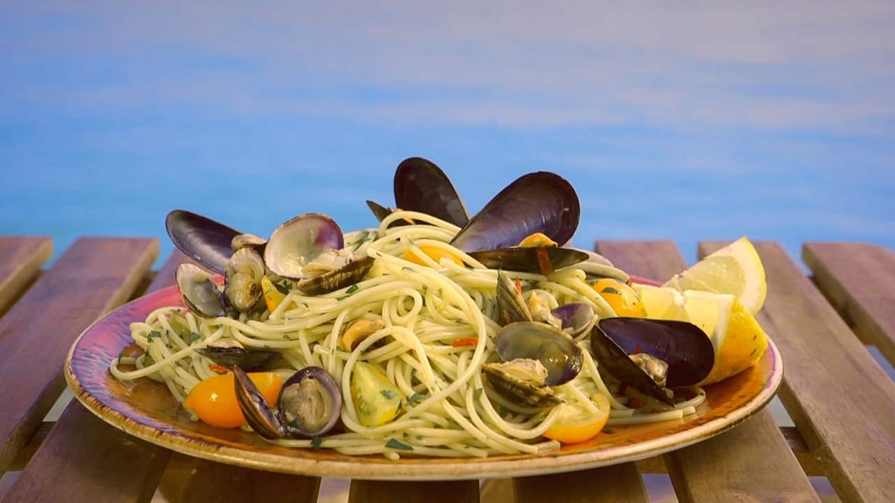 A spaghetti and seafood dish sits on a wooden table.