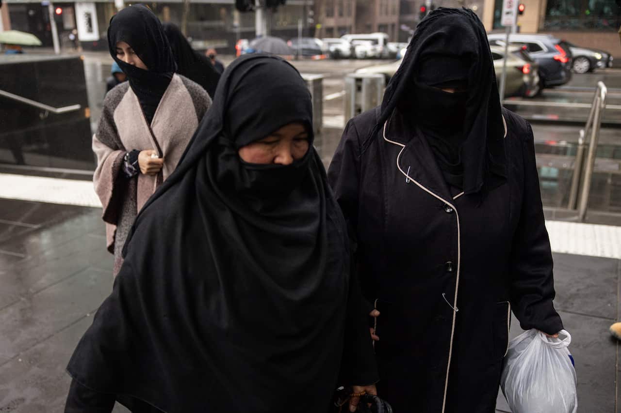 Two women wearing black walk to court. 