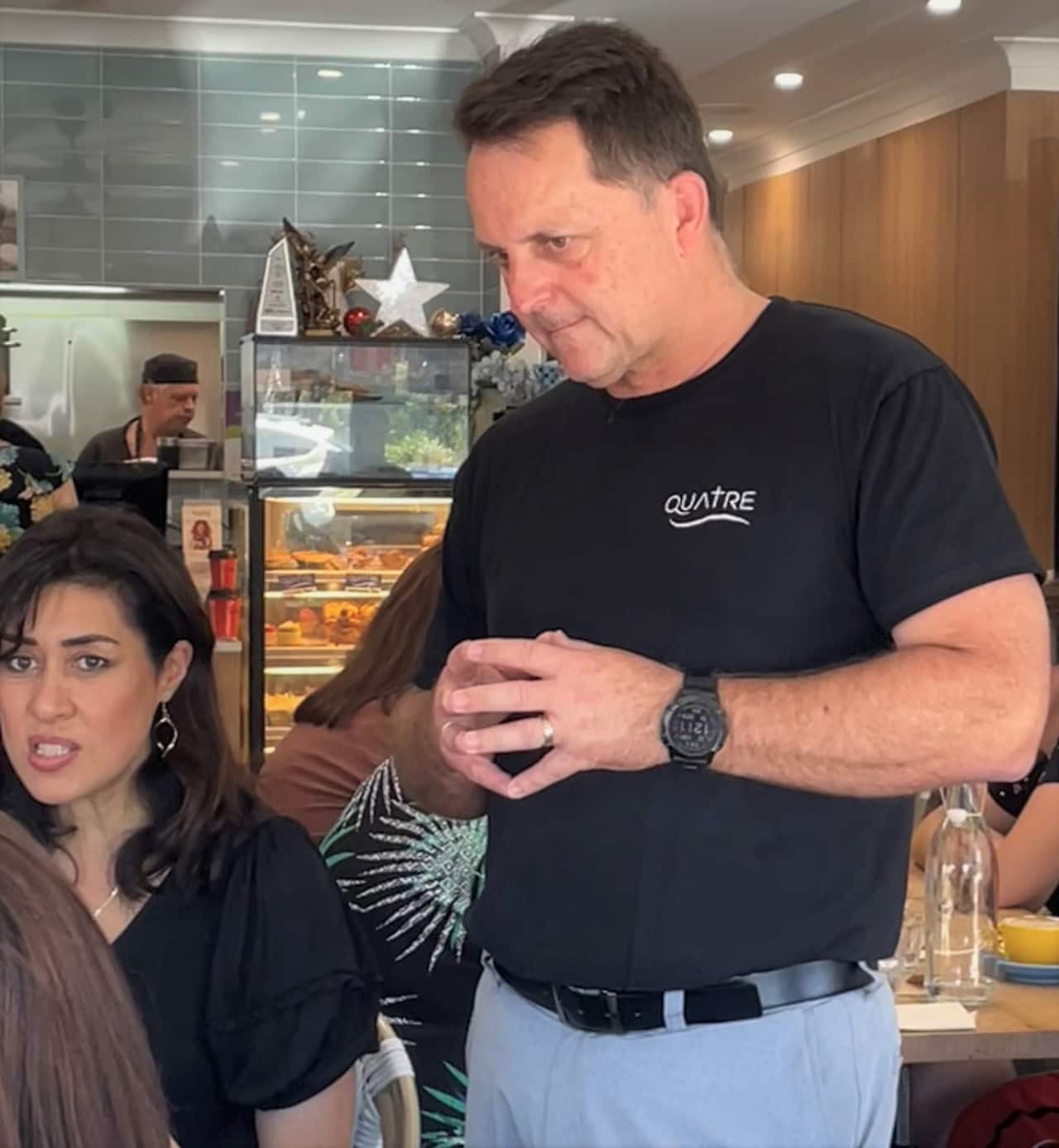 Craig Mackenzie in a black t-shirt serving at Quatre Cafe.