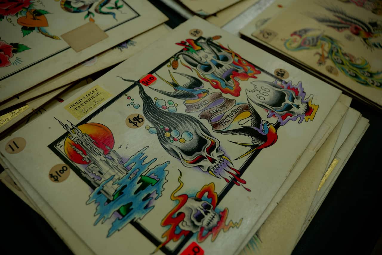 A pile of sheets covered with colourful tattoo designs on the table.