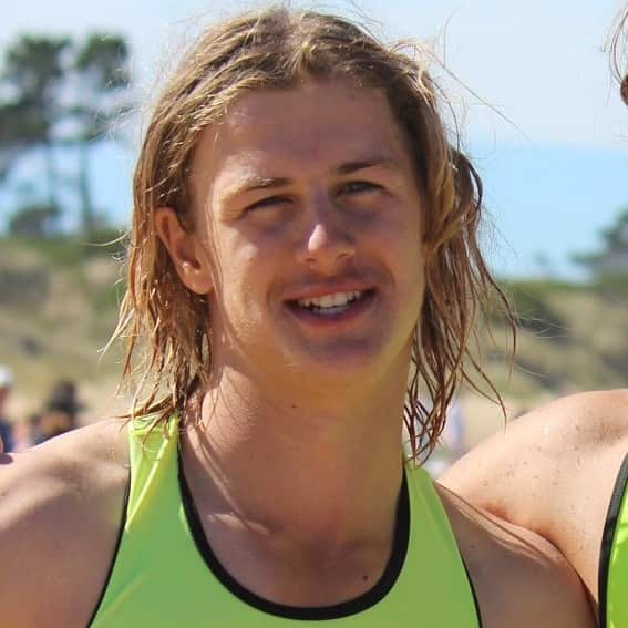 Close up of a young man with shaggy blonde hair on a beach