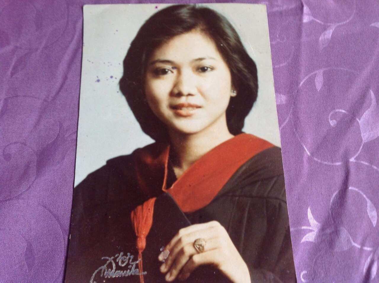 A photo on purple cloth of a woman (Julia's mother) wearing a graduation gown.