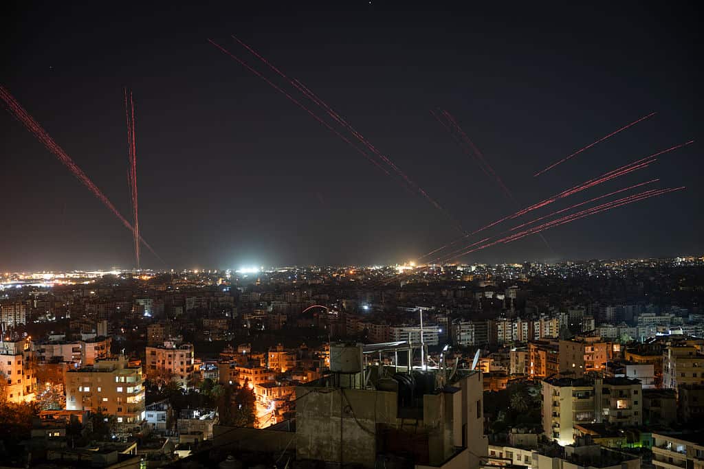 Bullets fly in the night sky over a city.