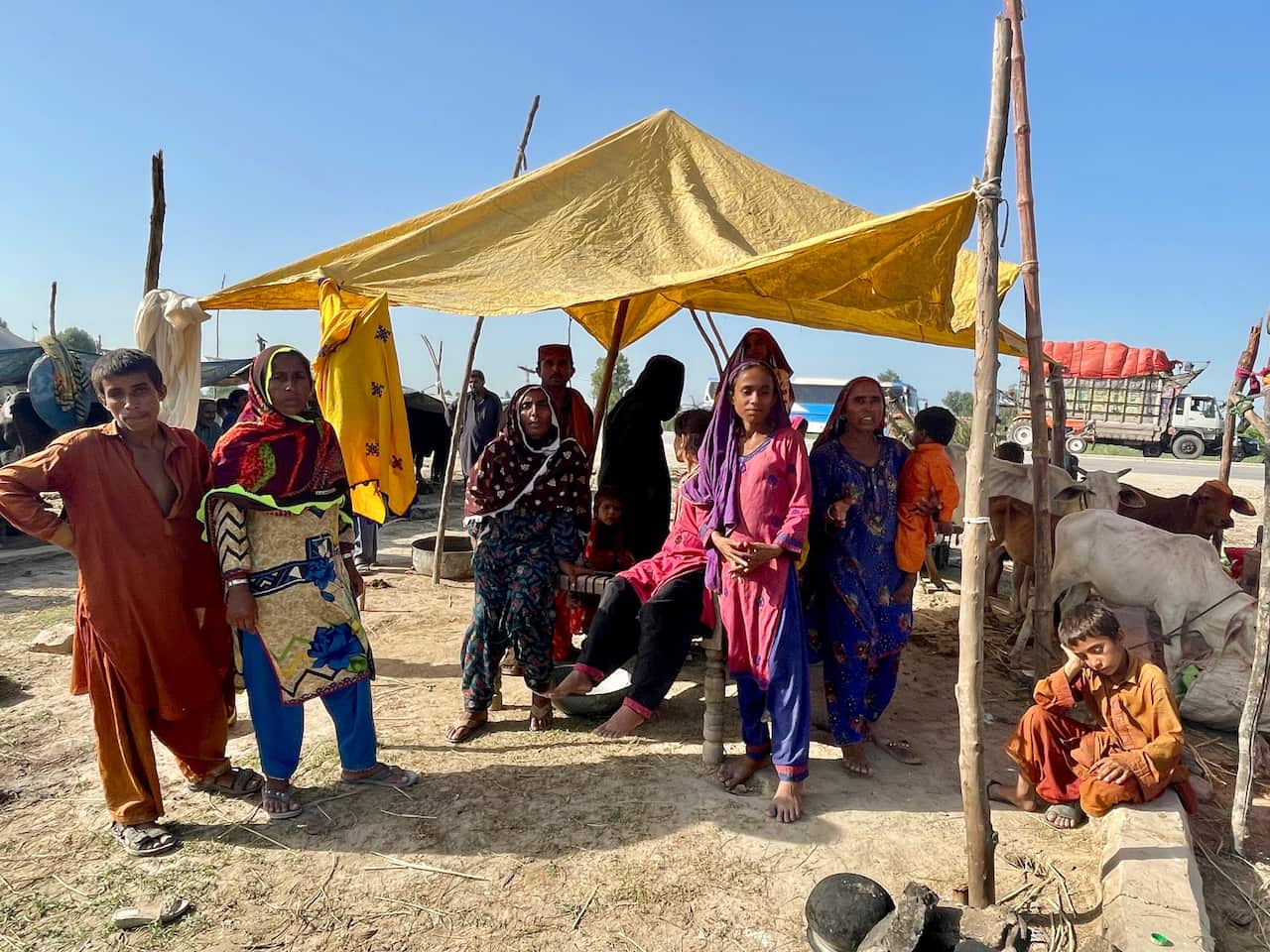 A group of people standing outside under a makeshift shelter.