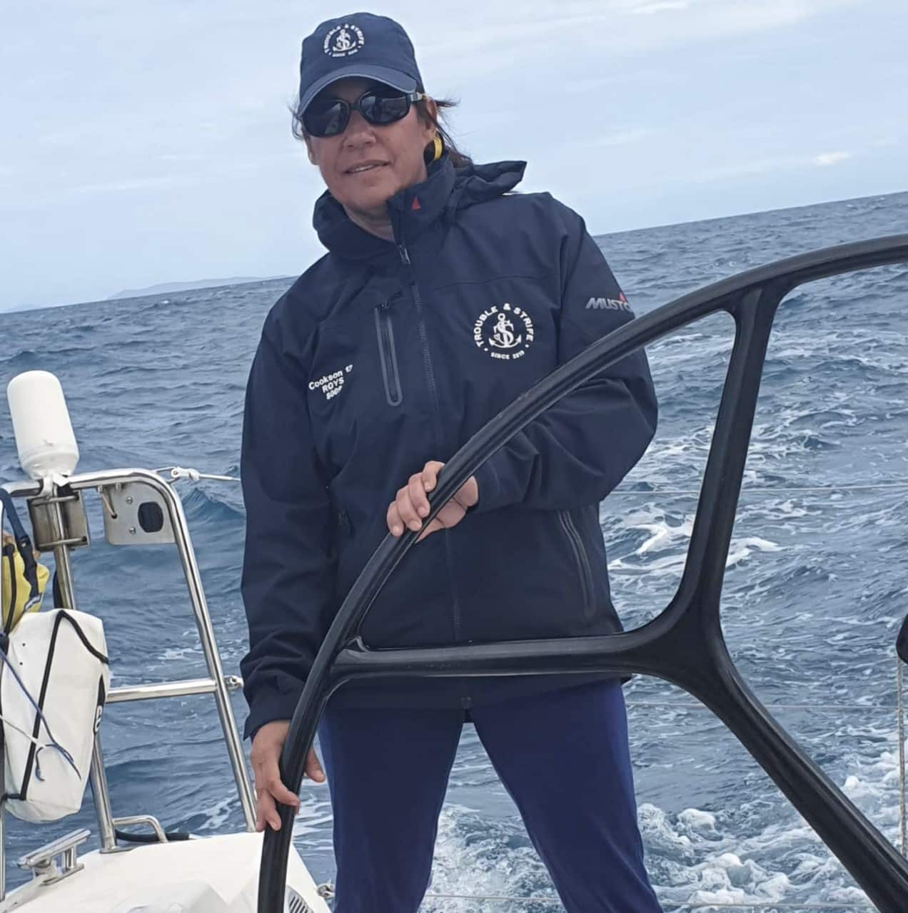 Angelina Hadwen at sea, holding the steering wheel of a boat. 