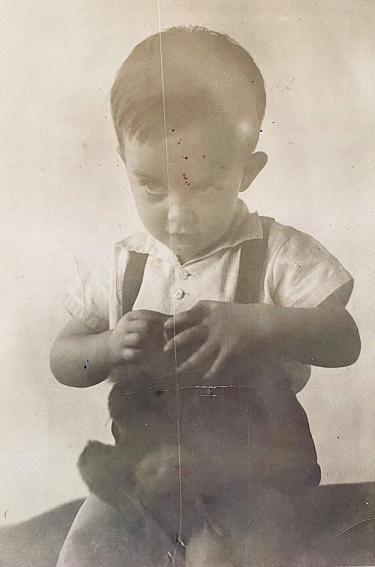 a black and white photo from the 1930s of a toddler boy in a white shirt and overalls