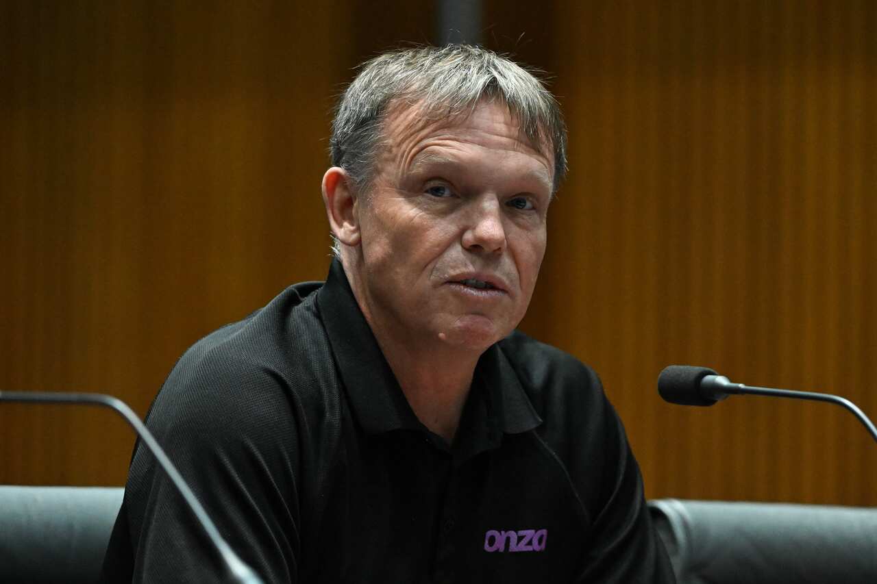 A man with a black collared shirt speaks into a microphone