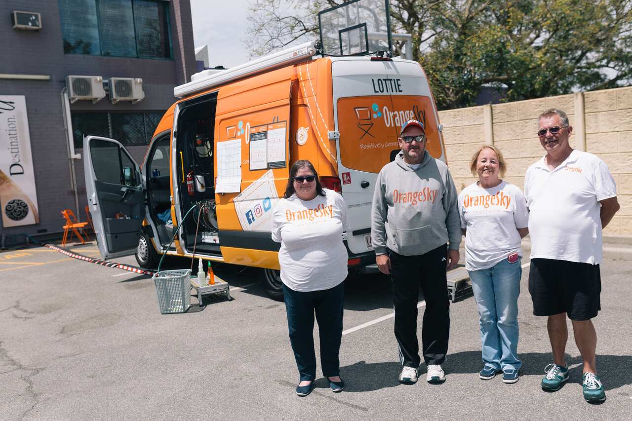 Four people standing outside in front of a van.