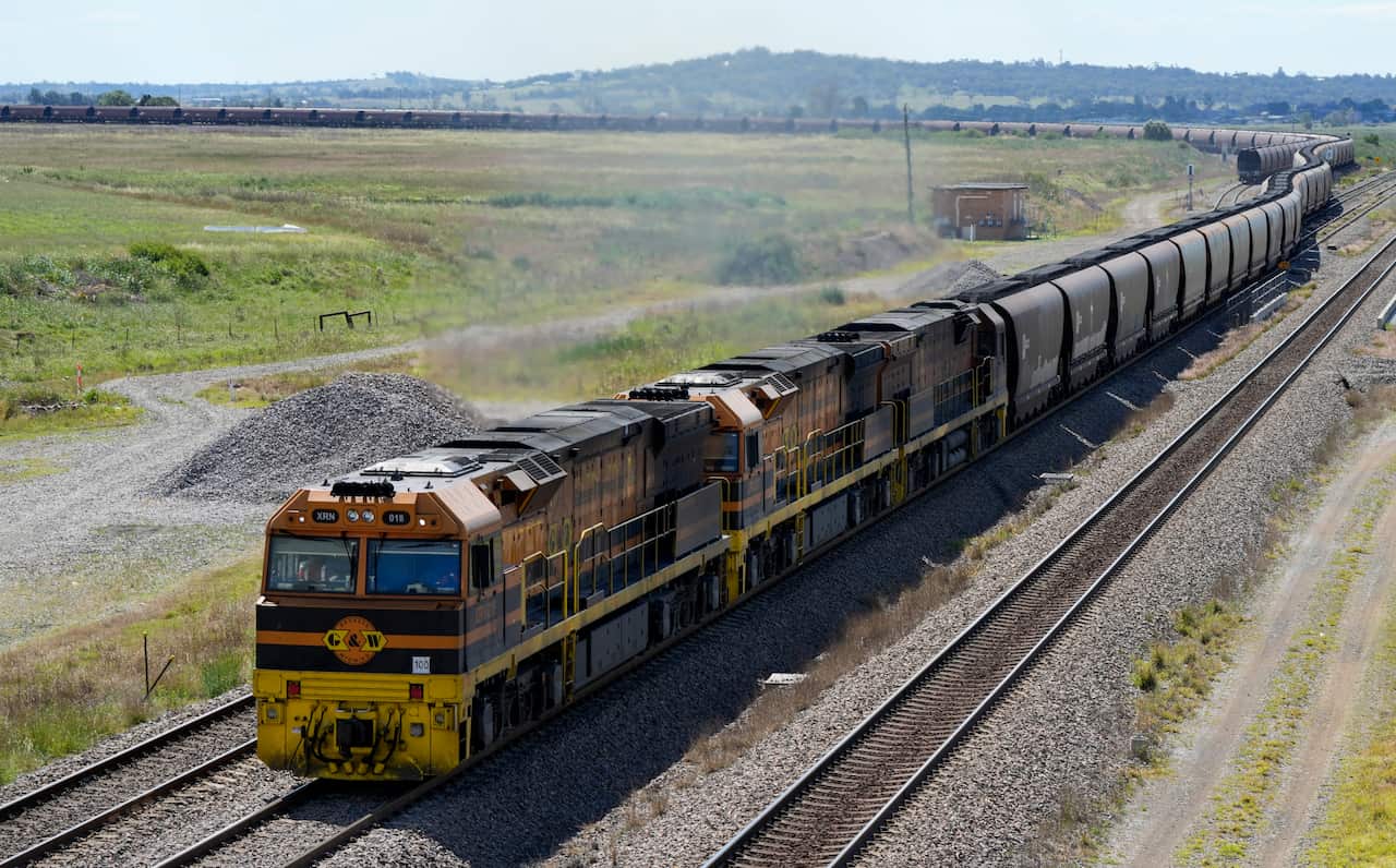 A train covered in black soot travels through the countryside.